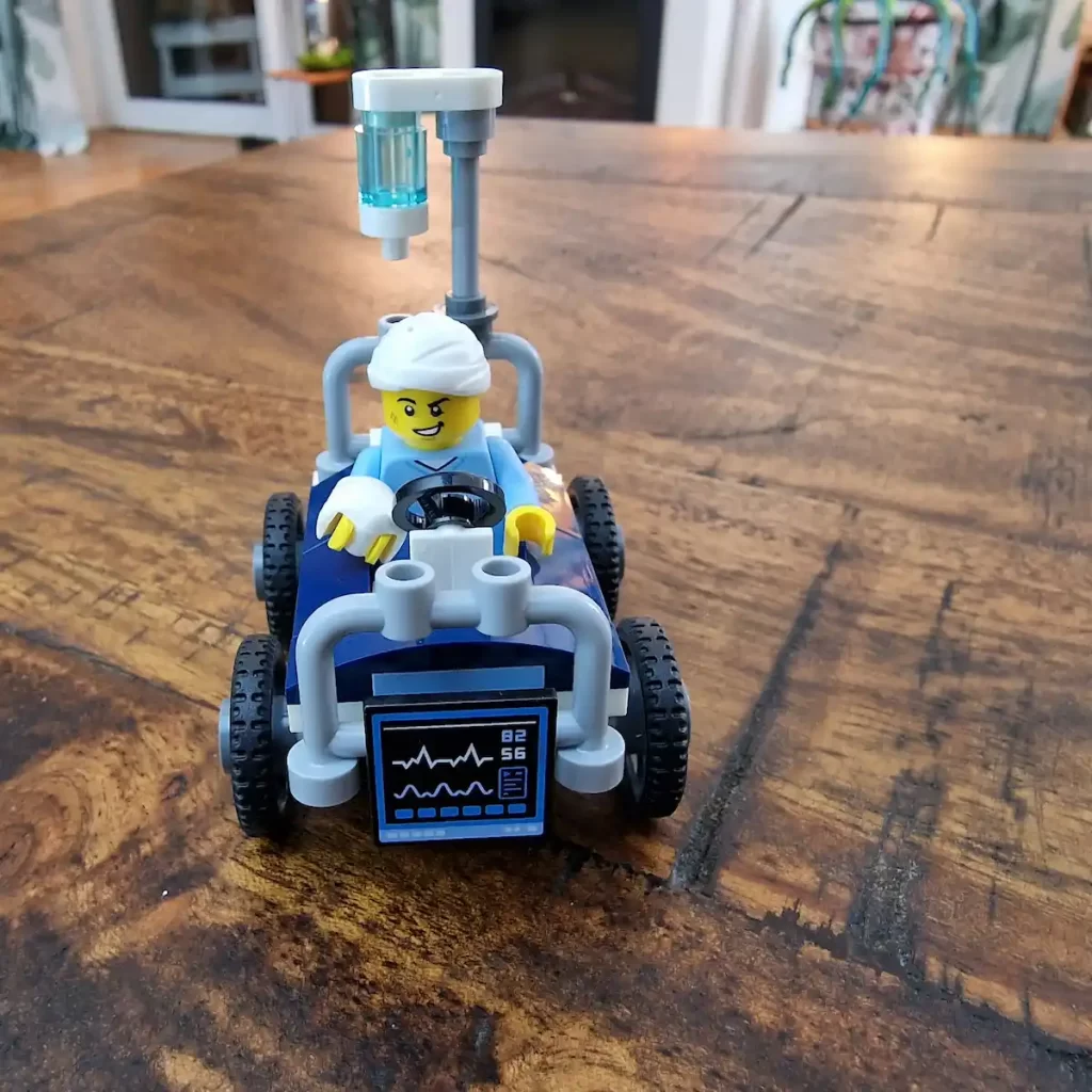 the racer sitting on the hospital bed of LEGO City 60459 Airplane vs. Hospital Bed Race Car Pack Photo taked by angelofdeathWHV